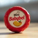 Babybelletje mini cheese snack wrapped in red wax showing creamy texture inside